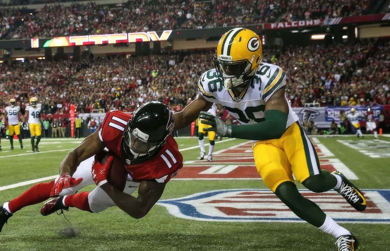 Atlanta Falcons wide receiver dives into the endzone while being tackled by a Green Bay Packers defender during an NFL game.