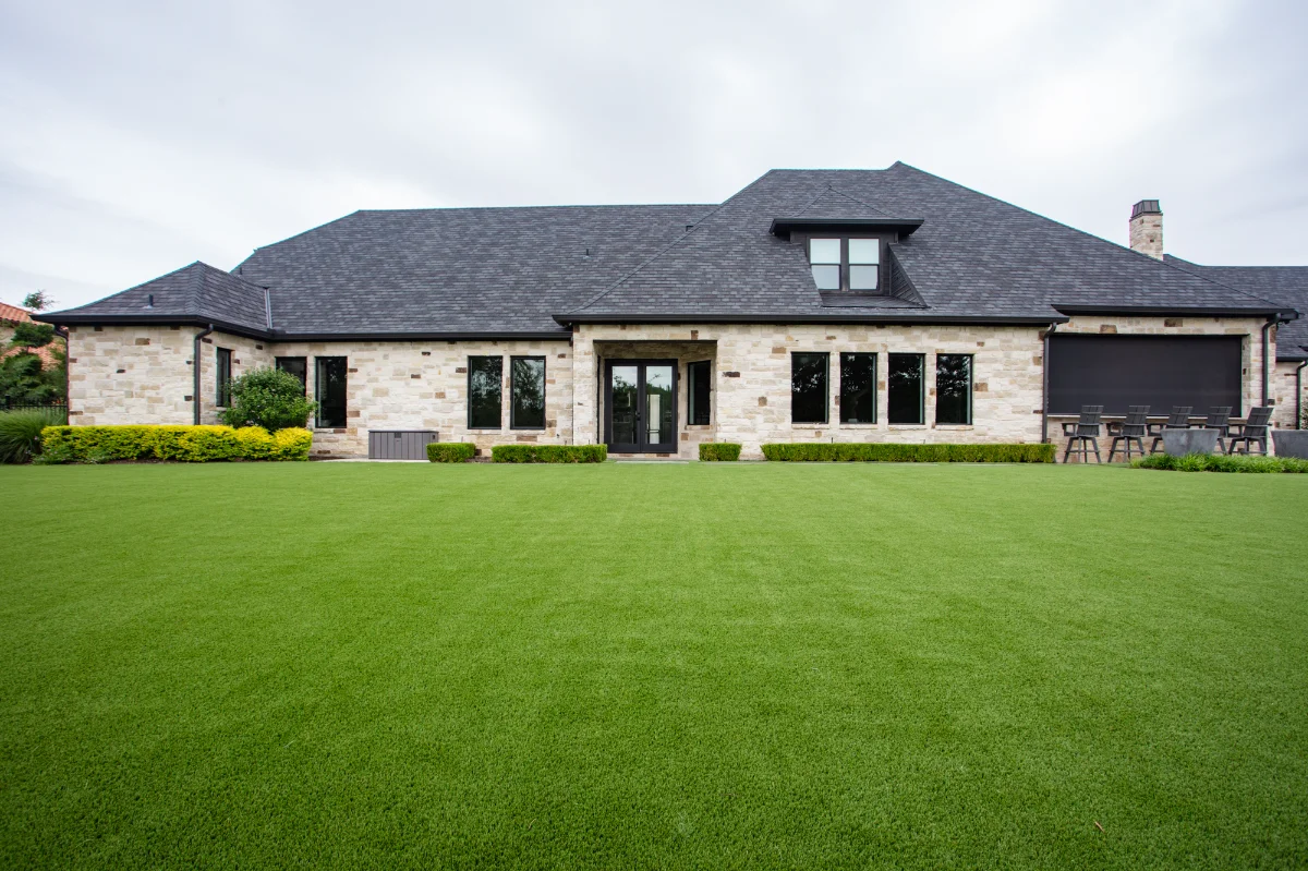 Artificial Lawn Turf Artificial Lawn Turf installed in a residential backyard behind a large house