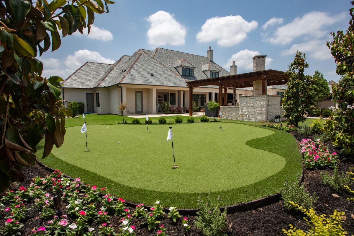 Artificial Putting Green with 4 holes surrounded by flower beds in a backyard