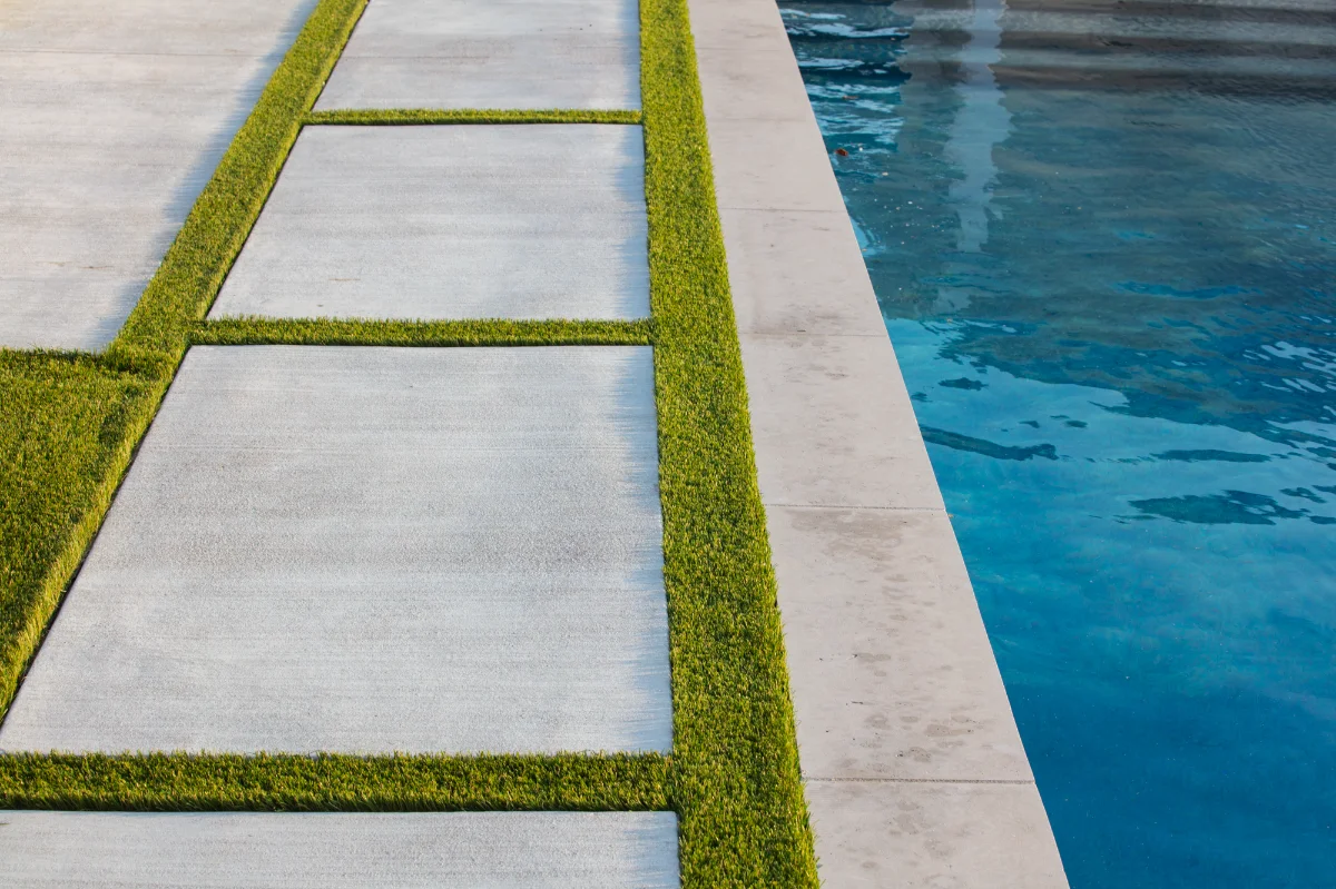 Synthetic Pool Turf Strips around pavers next to a pool