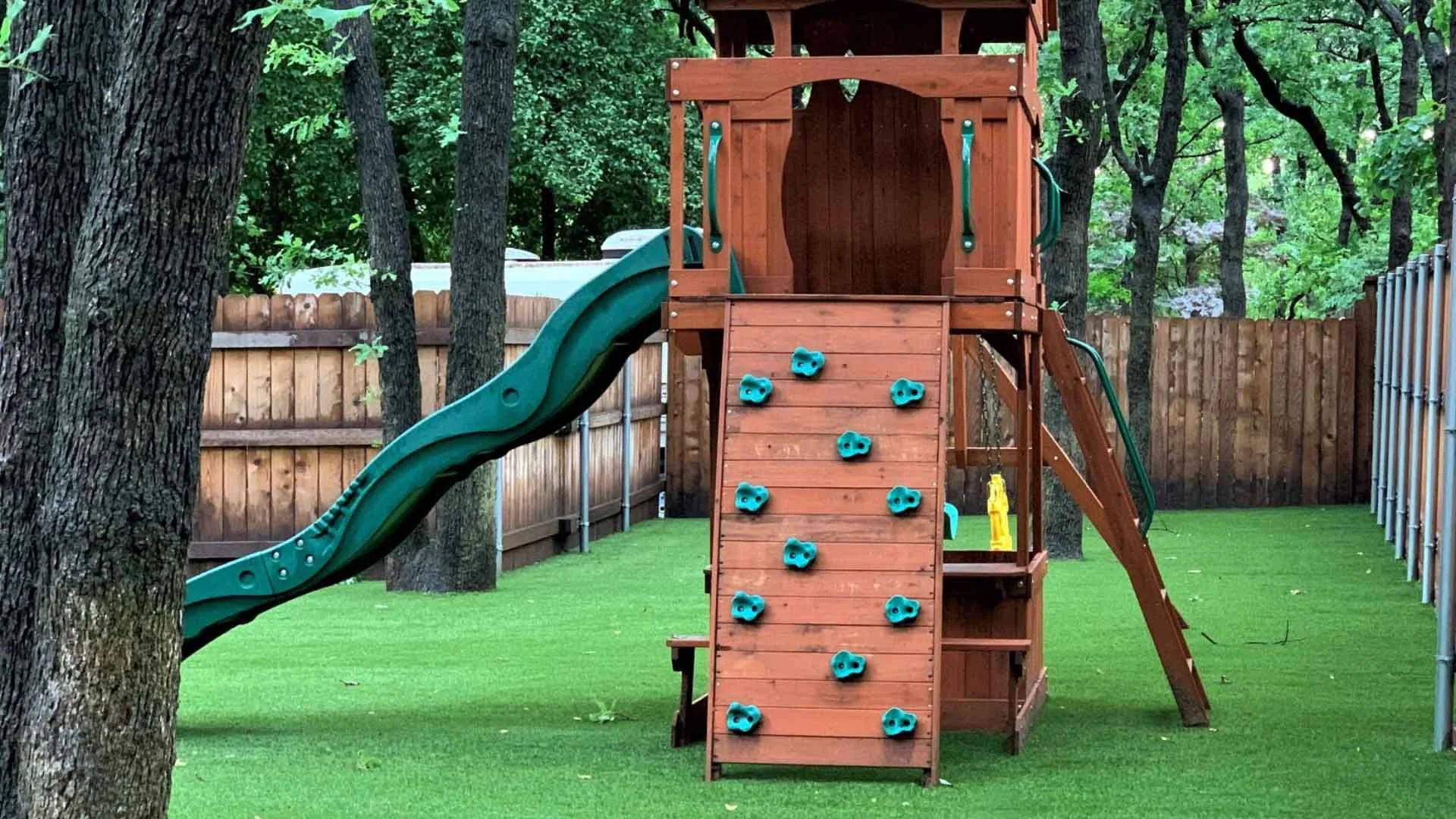 Synthetic Grass Playground with a slide an climbing wall playset