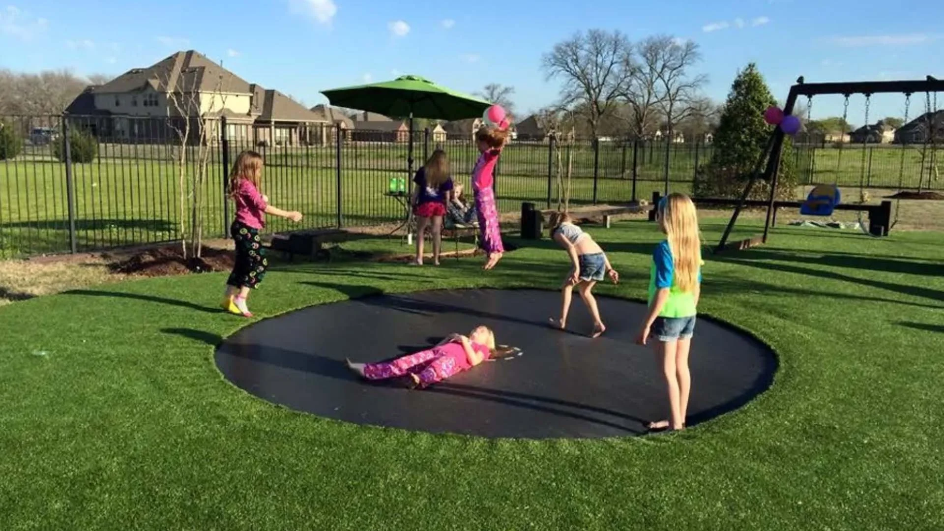 Synthetic Turf Playground with an inground trampoline and kids jumping on it