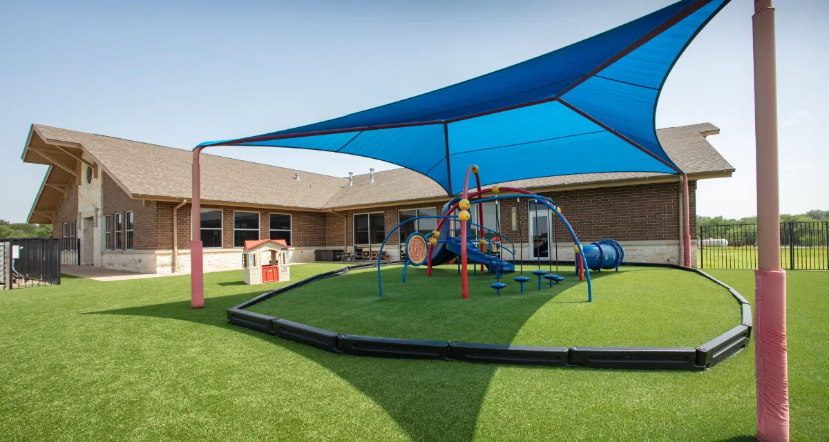 Artificial Turf Playground with play equipment and a sun sail