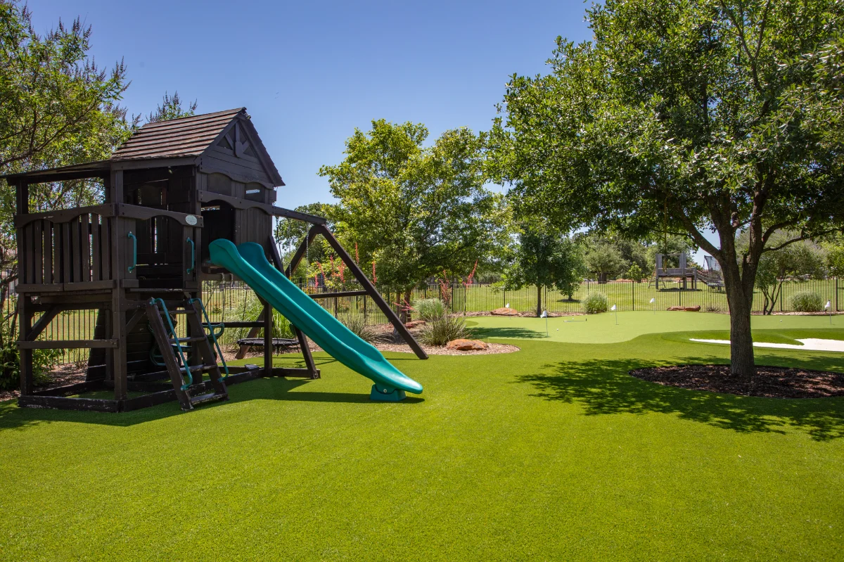 Artificial Grass Playground with a play set and slide in a backyard